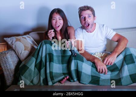 Junge gemischte Rasse attraktives Paar mit asiatischen Koreanerin und weißen Mann genießen zusammen Fernsehen Comedy-Film lachen glücklich und aufgeregt Stockfoto