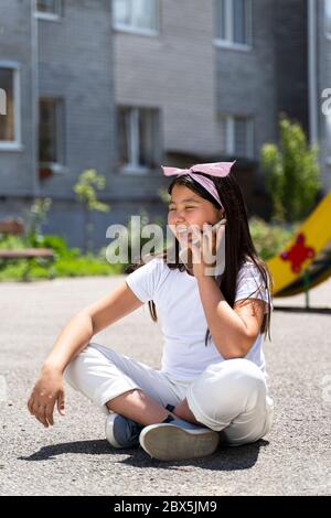 Schöne asiatische Mädchen auf dem Boden sitzen und reden Das Telefon Stockfoto