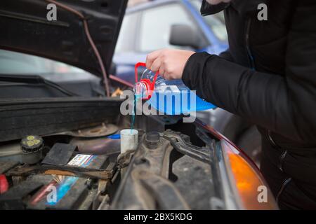 Detail auf Gießen Frostschutzmittel Flüssigkeit Bildschirm waschen in schmutziges Auto aus blauen Frostschutzwasser-Behälter, Auto-Konzept Stockfoto