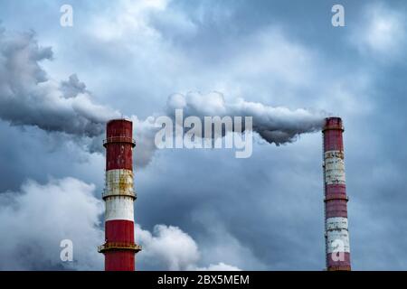 Dunkle giftige Rauchwolken, die aus dem Fabrikschornstein kommen. Luftverschmutzung und Erderwärmung durch altes Industriekraftwerk Stockfoto