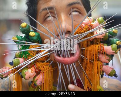 Der verzierte Thai-chinesische Taoist durchdringt seine Wangen und Lippen mit verzierten Stahlstiften/Spießen während des Phuket Vegetarian Festivals. Stockfoto