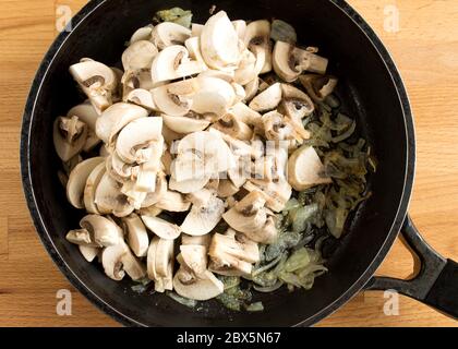 Pilze und Zwiebeln in einer Pfanne. Gebratene Pilze und Gemüse in Öl. Blick von oben ohne Leute. Stockfoto