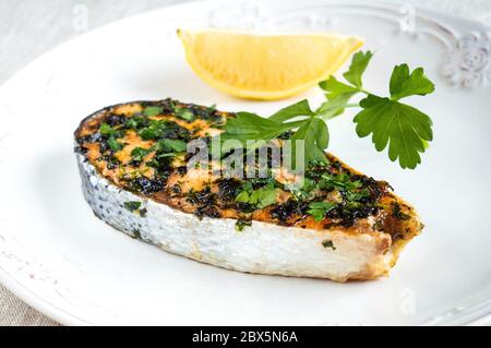 Lachs mit Petersilie und Zitrone auf einem weißen Teller. Servieren von rotem Fisch. Stockfoto