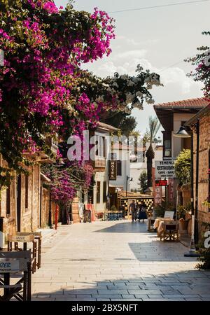 Sonnige Spazierstraße mit blühenden lila Blumen in Antalya historischen Zentrum - Kaleici, Türkei Stockfoto
