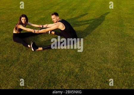 Athletischer Mann und Frau tun verschiedene Übung auf grünem Rasen Stockfoto