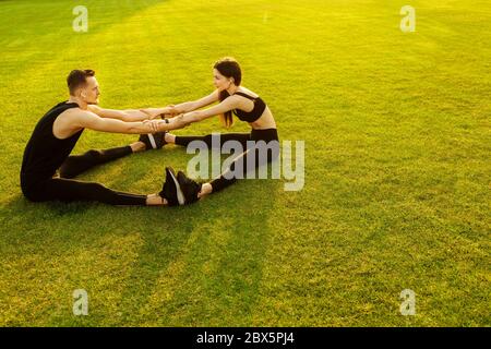 Athletischer Mann und Frau tun verschiedene Übung auf grünem Rasen Stockfoto