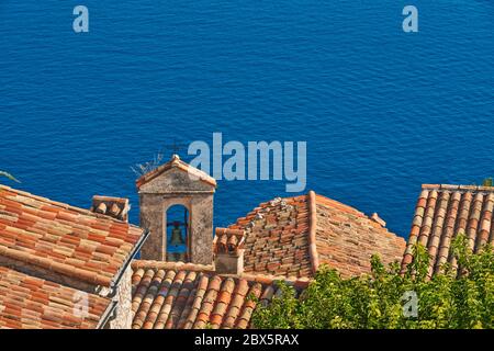 Terracotta Fliesen Dächer und Glockenturm des Dorfes Eze mit dem Mittelmeer. Französische Riviera, Alpes-Maritimes (06), Frankreich Stockfoto