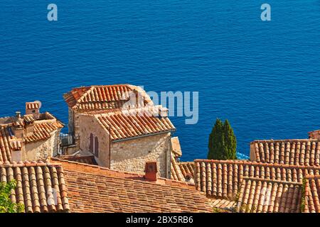 Terracotta Fliesen Dächer und Glockenturm des Dorfes Eze mit dem Mittelmeer. Französische Riviera, Alpes-Maritimes (06), Frankreich Stockfoto