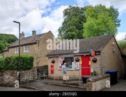 Eine Frau vor einem Postamt im Dorf Eyam, Derbyshire. Nachdem im Mai 1666 im Dorf Eyam der erste Fall der Beulenpest gefunden wurde, gingen die Dorfbewohner in eine selbstauferlegte Isolation, um zu verhindern, dass sich die Infektion auf die Nachbargemeinden ausbreitet. Ein Umfang von Steinen umgab das Dorf mit niemand erlaubt, die Grenze in beiden Richtungen bis November 1667 zu überqueren. Stockfoto