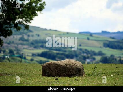 Der Boundary Stone am Rande des Dorfes Eyam in Derbyshire hinterließen die Menschen aus Eyam während der Pest Münzen in Löchern im Stein, die sie mit Essig füllten, in der Hoffnung, die Krankheit zu töten. Benachbarte Gemeindemitglieder hinterließen im Gegenzug Essen. Nachdem im Mai 1666 im Dorf Eyam der erste Fall der Beulenpest gefunden wurde, gingen die Dorfbewohner in eine selbstauferlegte Isolation, um zu verhindern, dass sich die Infektion auf die Nachbargemeinden ausbreitet. Ein Umfang von Steinen umgab das Dorf mit niemand erlaubt, die Grenze in beiden Richtungen bis November 1667 zu überqueren. Stockfoto