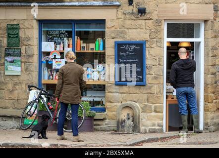 Menschen soziale Distanz außerhalb eines Cafés serviert Essen zum Mitnehmen im Dorf Eyam, Derbyshire. Nachdem im Mai 1666 im Dorf Eyam der erste Fall der Beulenpest gefunden wurde, gingen die Dorfbewohner in eine selbstauferlegte Isolation, um zu verhindern, dass sich die Infektion auf die Nachbargemeinden ausbreitet. Ein Umfang von Steinen umgab das Dorf mit niemand erlaubt, die Grenze in beiden Richtungen bis November 1667 zu überqueren. Stockfoto