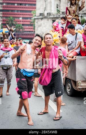 Junge philippinische Männer scherzen herum, bevor sie auf die berühmte jährliche Black Nazarene Religious Parade in Manila auf den Philippinen aufbrechen. Stockfoto