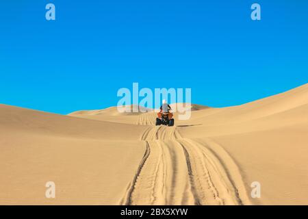 Quad-Fahrende - ein glücklicher Biker in Sandwüstendünen, Afrika, Namibia, Namib, Walvis Bay, Swakopmund. Stockfoto