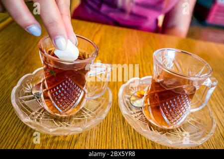 Die Hand der Frau, die in Petra, Jordanien, einem von zwei tot-Gläsern Tee zuschüttet. Stockfoto