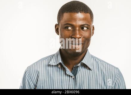Lächelnder afroamerikanischer Mann, der auf Seite schaut. Dunkelhäutiger junger Mann im gestreiften Hemd isoliert auf weißem Hintergrund. Tonbild Stockfoto