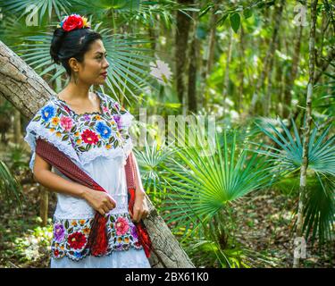 Tulum, Quintana Roo, Mexiko- Februar 24,2020: Eine schöne mexikanische Frau wartet im Dschungel in ihrem Huipil-Kleid, einer traditionellen Yucatán-Tracht Stockfoto