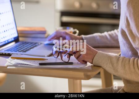 Mann freiberuflich arbeitet im Home Office auf Laptop, konzentrieren sich auf Brillen in der Hand. Fernarbeit, Remote-Online-Arbeit Stockfoto