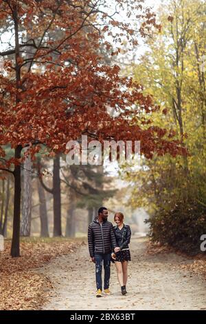 Glücklich interracial Paar zu Fuß im Herbst Park, schwarzer Mann und weiß Rotschopf Frau Stockfoto