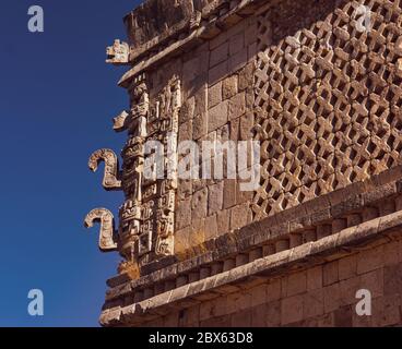 Ecke des Maya-Tempels mit detaillierten Steinschnitzereien, die Maya-Götter und Symbole in Uxmal, Mexiko, darstellen Stockfoto