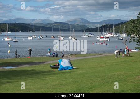 Besucher, einschließlich Wassersportler, genießen einen sonnigen Sommertag im Fell Foot Park auf Windermere im Lake District National Park Stockfoto