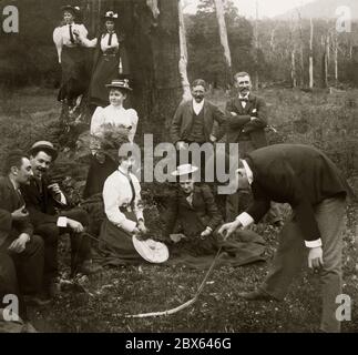 Eine Gruppe aus BushWalking posiert für die Kamera in Victoria, Australien c.. 1900. Nachdem er auf eine tote Schlange gestoßen ist, nimmt ein Mann sie vorsichtig am Schwanz auf. Die Frauen und Männer sind modisch in ganz formelle Kleidung für einen solchen Ausflug gekleidet. Sie sind von Eukalyptus und Farnen umgeben. Stockfoto