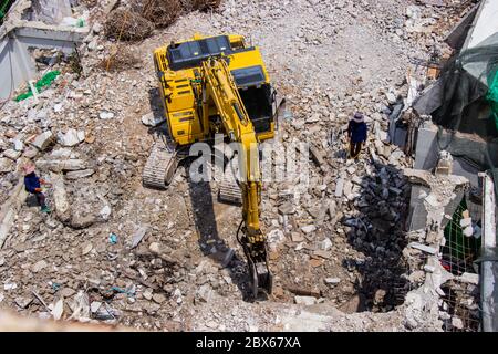 Der Tieflöffel Maschinen arbeiten vor Ort Abriss eines alten Gebäudes Arbeiter Spritzwasser, Staub zu erhalten. Stockfoto