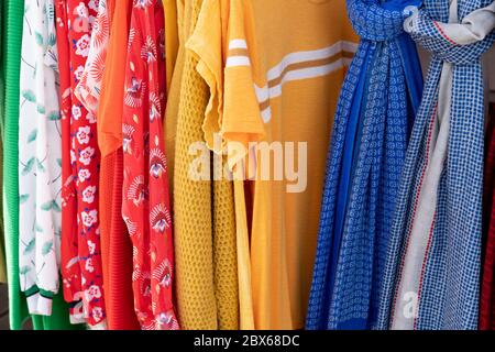 Regenbogenfarbene Kleidung an Kleiderbügeln im Einzelhandel im Mode- und Einkaufskonzept Stockfoto