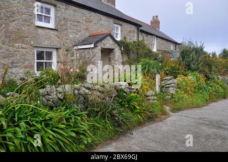 Ferienhäuser mit Blumen bedeckten Kieswänden auf der Straße von der höheren Stadt zum Kai auf St. Martins eine der fünf bewohnten Inseln in den Inseln von Sci Stockfoto