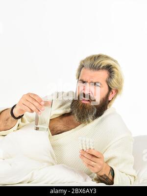 Überschläfring kann Körper in Gefahr für metabolische Probleme setzen. Kater Konzept. Mann schmerzhafte Leidenden Gesicht Aufwachen am Morgen. Hipster trinken Wasser Nehmen Sie Medikamente. Kopfschmerzkater. Abhilfe durch Kater. Stockfoto