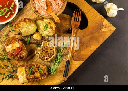 Gebackene gefüllte Kartoffeln mit Speck, Chili und Käse, Draufsicht. Gebackener Knoblauch. Hausgemachte Speisen. Vorbereiten einer Beilage zum Grillen. Stockfoto