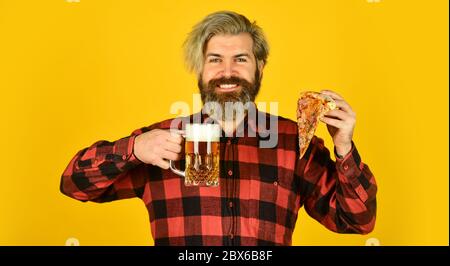 Happy bärtigen Mann mit Bier und Pizza. italienisches Essen. italien ist hier. Kerl in der Bar Bier trinken und Pizza essen. Prost. Ein Glas Bier und Pizza. Fußball im Fernsehen. Fast Food. Stockfoto