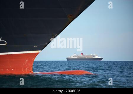 Cunard Kreuzfahrtschiff Queen Victoria mit dem Liner Queen Mary 2 in der Ferne, vor Anker in Weymouth Bay, Dorset, Großbritannien, während der Coronavirus-Sperre Stockfoto