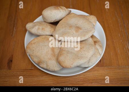Ein halbes Dutzend frisch gebackener flacher Pitta-Brote auf einem weißen Teller Stockfoto