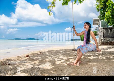 Schöne Frau, die auf einer Schaukel am Strand sitzt Phuket Stockfoto