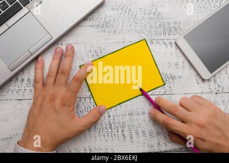 Hand halten, beachten Sie Papier in der Nähe schreiben Ausrüstung und modernen Smartphone Gerät Stockfoto