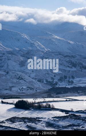 Winterszene, aufgenommen bei einer Abfahrt vom Latrigg Fell, mit Castlerigg Steinkreis im Schnee vor der Kulisse der nördlichen zentralen Fjälls hervorgehoben. Stockfoto