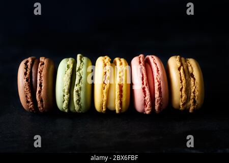 Reihe von bunten Macarons Nahaufnahme auf schwarzem Hintergrund. Horizontales Bild Stockfoto