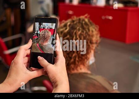 Friseur macht ein Foto von ihrer Arbeit nach dem Schneiden ein Haare des Kunden Stockfoto