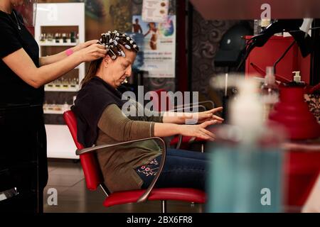 Die Kundin eines Friseurs streicht mit ihren Händen, während sie gerade ist Gekämmt Stockfoto