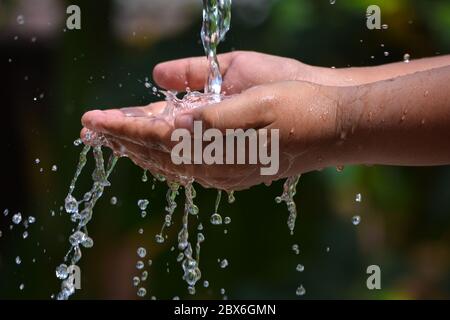 Wasser Gießen in Kind zwei Hand auf Natur Hintergrund. Hände mit Wasserspritzern. Stockfoto