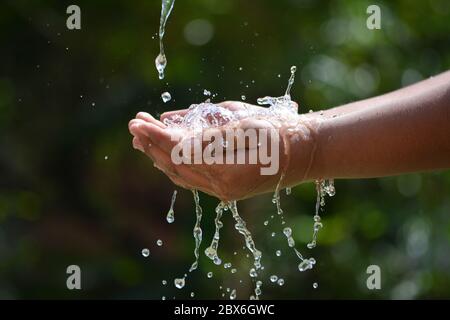 Wasser Gießen in Kind zwei Hand auf Natur Hintergrund. Hände mit Wasserspritzern. Stockfoto