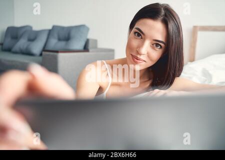 Lächelnd junge Brünette Öffnung Laptop und arbeiten Stockfoto