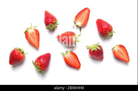 Reife rote Erdbeeren mit Grüns isoliert auf weißem Hintergrund, Beerenmuster, Draufsicht Stockfoto