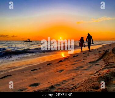 Paares Silhouette am Strand bei Sonnenuntergang mit Boot im Hintergrund. Grand Bahia Principe Strand in Punta Cana, Dominikanische Republik. Stockfoto