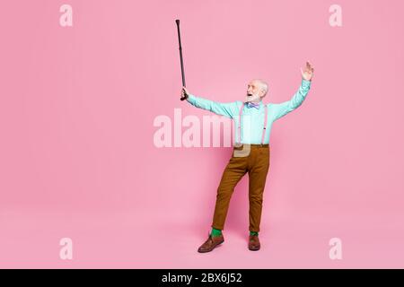 Full Size Foto von aktiven verrückt Opa bewegenden Tanz Senior Party heben gehen Stick tragen Mint Hemd Hosenträger Fliege Hose Schuhe grüne Socken Stockfoto