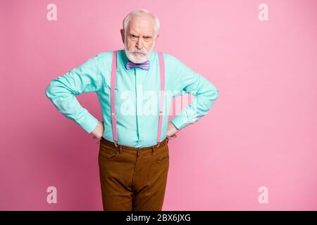 Foto von verrückten verrückten Mann im Alter Hände an Seiten wütend Grimasse Schuld Kinder für verderben Möbel tragen Minze Hemd Hosenträger Fliege Hose isoliert Stockfoto