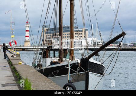 Der alte Leuchtturm im Binnenhafen von Malmö, Schweden mit einem alten Boot im Vordergrund Stockfoto