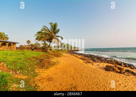 Strand mit rotem Sand und schwarzen Felsen mit blauem Himmel in Congo Town, Monrovia, Liberia Stockfoto