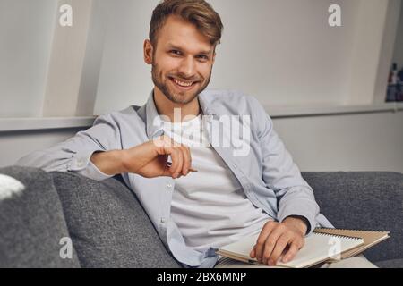 Mann, der seinen Ellbogen auf die Rückseite des Sofas lehnt Stockfoto