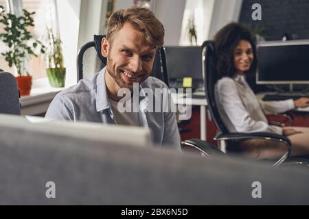 Zwei moderne Mitarbeiter sitzen an ihren Arbeitsplätzen Stockfoto